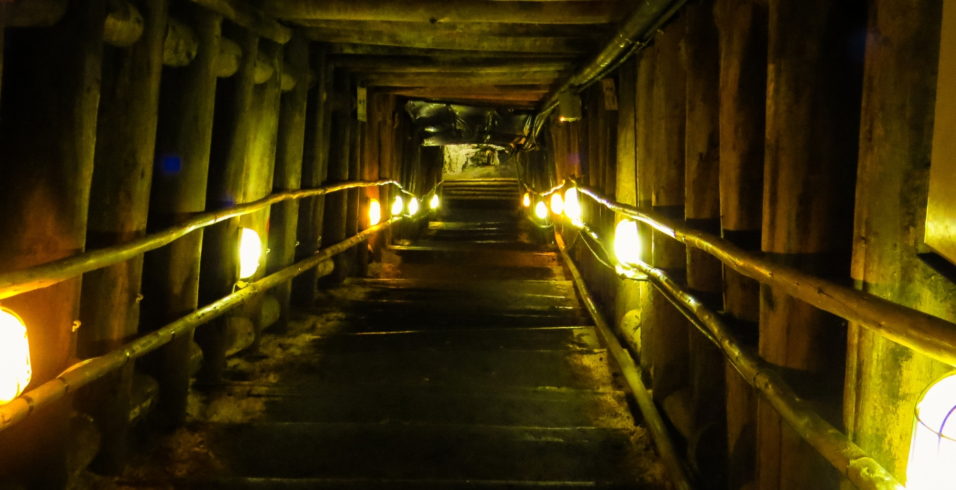 Egyiptom, piramis belső járata: sárga lámpákkal megvilágított, szűk, fagerendákkal dúcolt alagút és lépcsősor a mélybe.