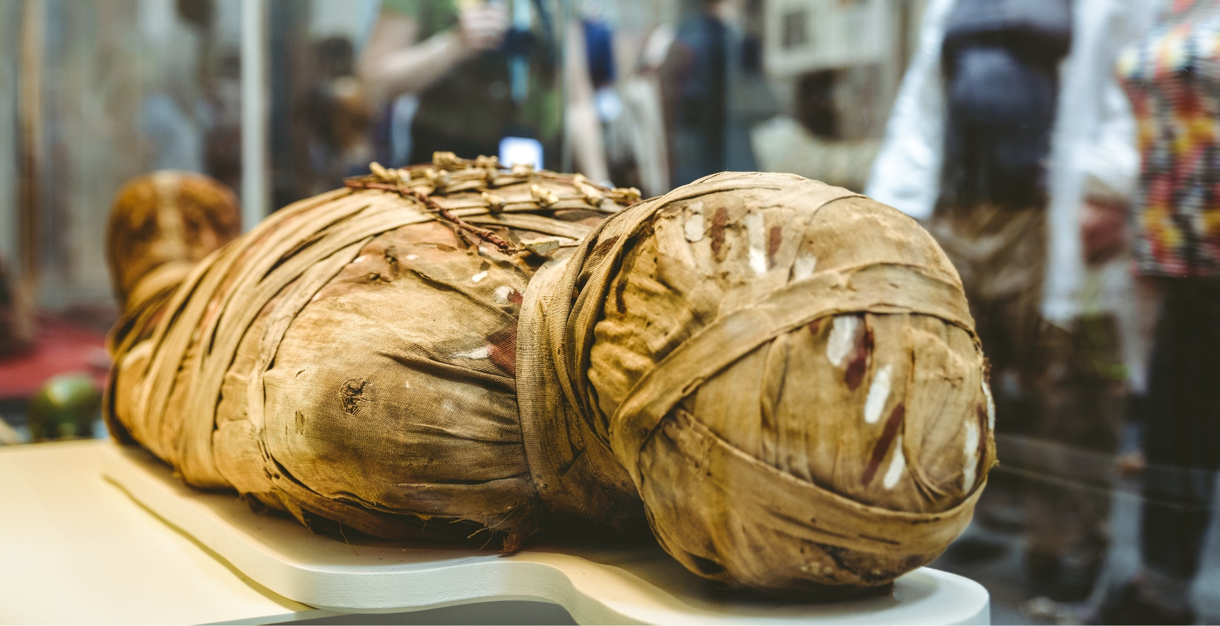 Közeli felvétel egy múmia felirat nélküli, barna lenvászon pólyákba tekert fejrészéről egy múzeumi tárlóban.